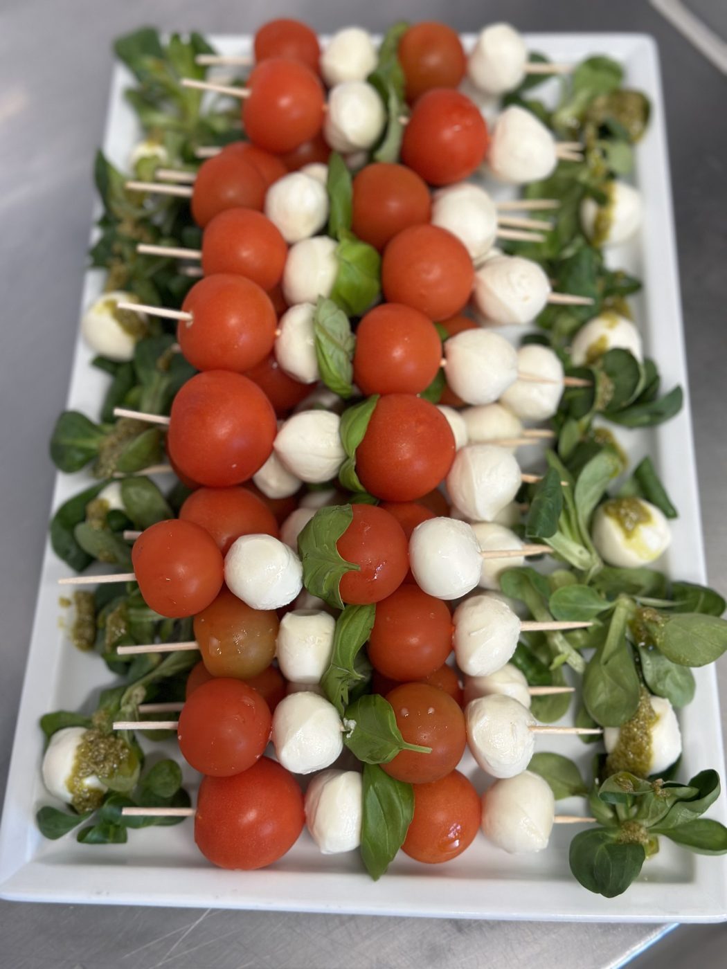 Caprese-Spieße mit Tomate, Mozzarella und Basilikum auf einer langen Platte