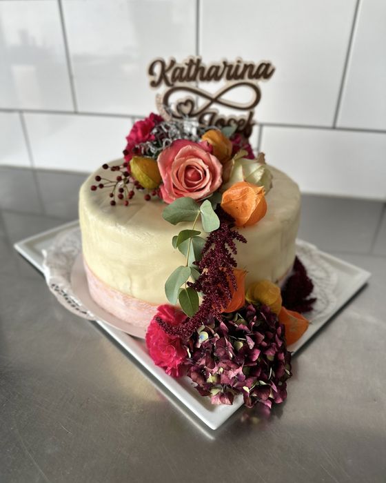 Hohe Festtagstorte mit Blumen und Namens-Topper